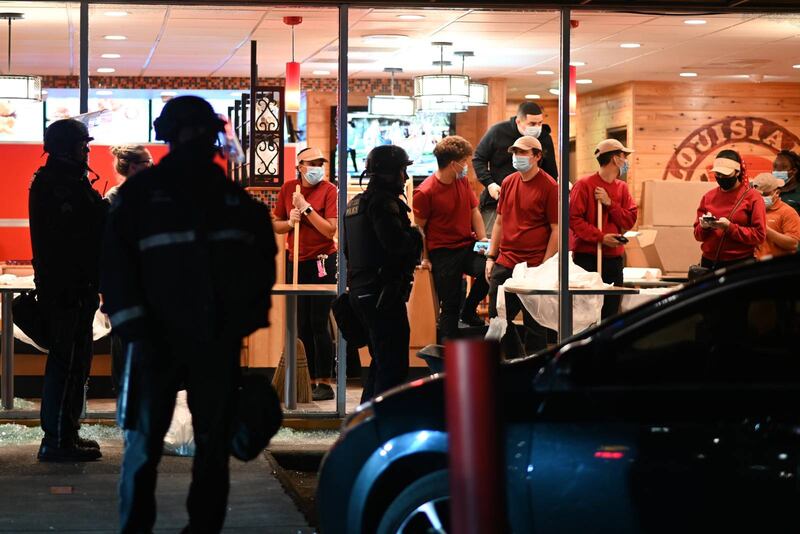 Workers at a Northeast Portland Popeyes clean up shattered glass.