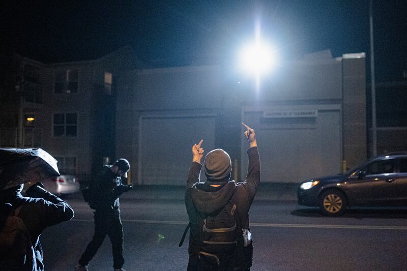 A protester gives two middle fingers to a police building.